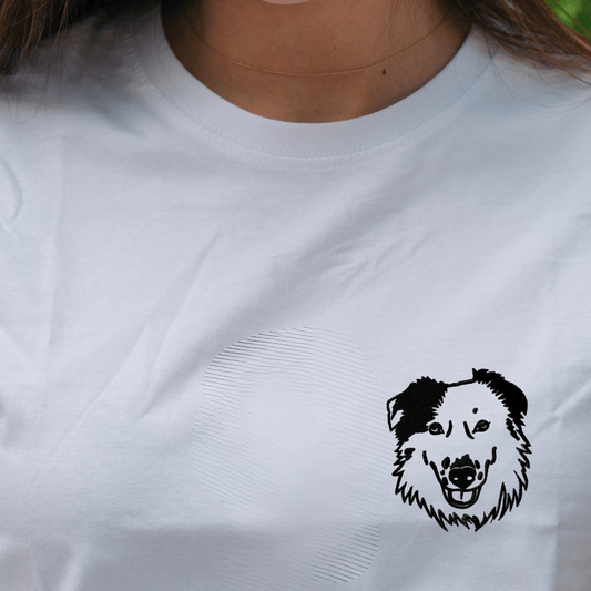 Detalle del bordado minimalista con cara de mascota en camiseta blanca
